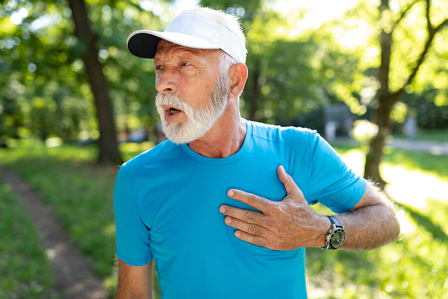 senior man wearing a blue shirt with chest pain in a park image