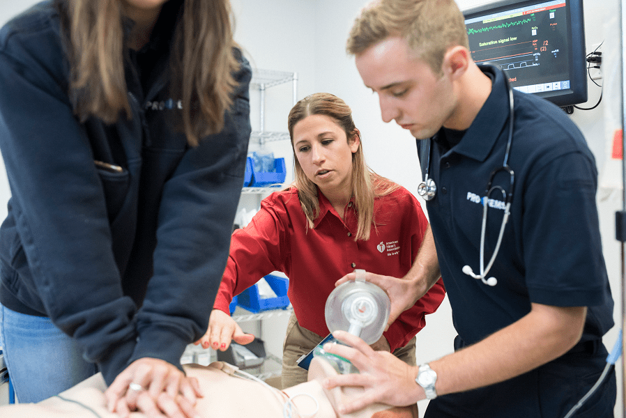 instructor teaching triage CPR to two students